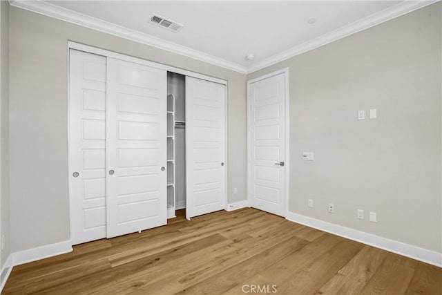 unfurnished bedroom with baseboards, wood finished floors, visible vents, and crown molding