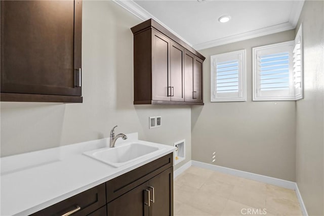 laundry area featuring washer hookup, crown molding, cabinet space, a sink, and baseboards