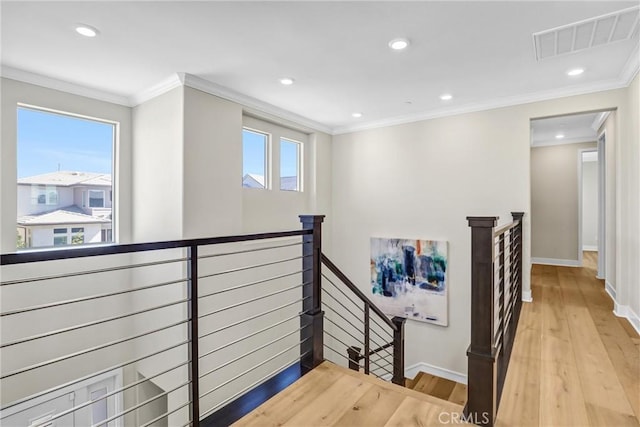 hall with crown molding, visible vents, a wealth of natural light, and an upstairs landing