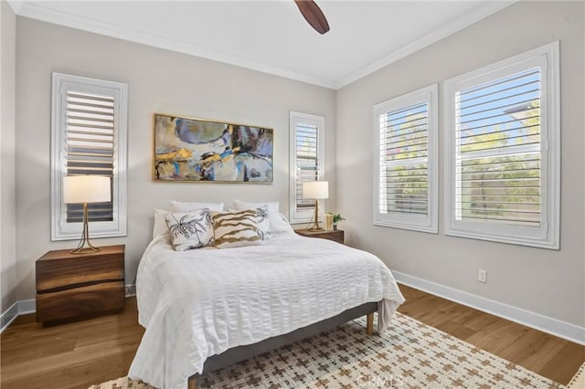 bedroom featuring baseboards, wood finished floors, a ceiling fan, and crown molding