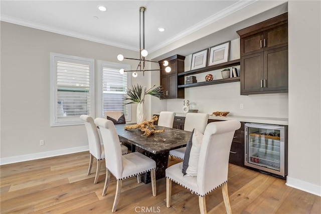 dining room with beverage cooler, ornamental molding, light wood-type flooring, and baseboards