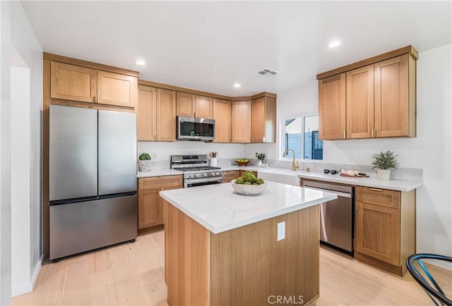 kitchen with a center island, light wood-type flooring, recessed lighting, appliances with stainless steel finishes, and a sink