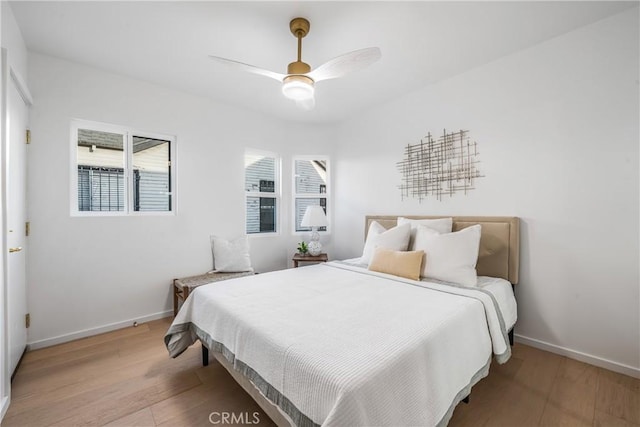 bedroom with ceiling fan, light wood finished floors, and baseboards