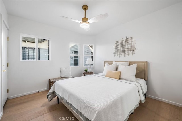 bedroom with a ceiling fan, light wood-style floors, and baseboards