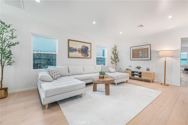 living room with light wood-style flooring, visible vents, baseboards, and recessed lighting