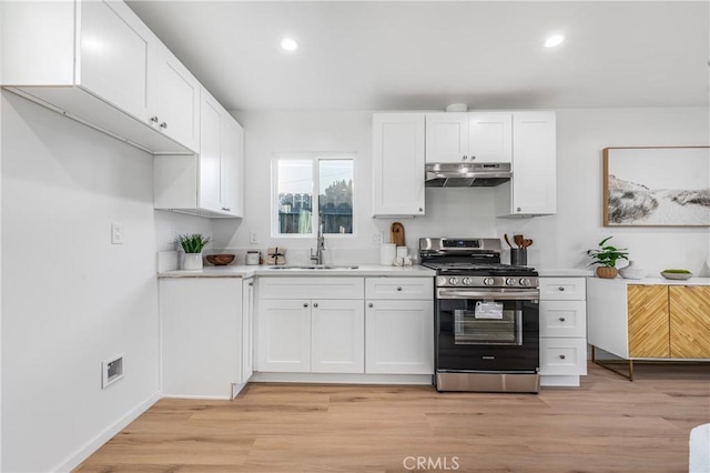 kitchen with white cabinets, stainless steel range with gas stovetop, under cabinet range hood, and a sink
