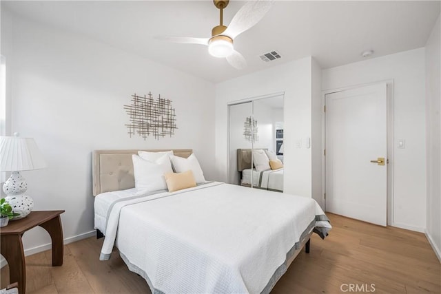 bedroom with light wood-type flooring, visible vents, a closet, baseboards, and ceiling fan
