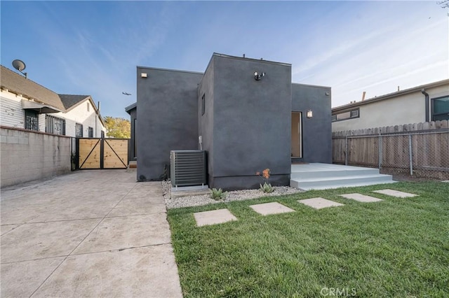 back of property featuring stucco siding, fence, and a gate
