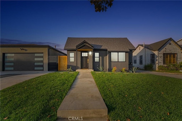 contemporary home with driveway, a shingled roof, a lawn, and stucco siding