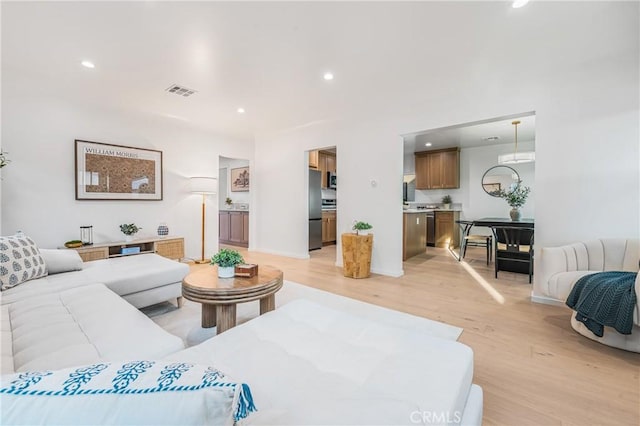 living room featuring recessed lighting, visible vents, baseboards, and light wood-style flooring