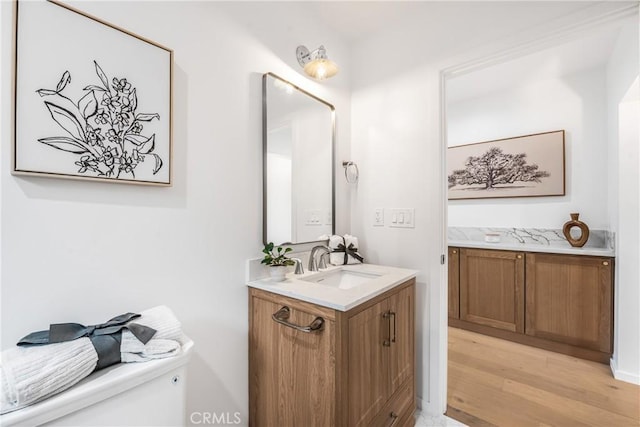 half bath featuring toilet, wood finished floors, and vanity