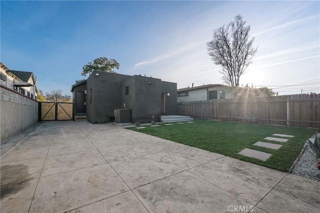 back of house with stucco siding, fence, cooling unit, and a gate