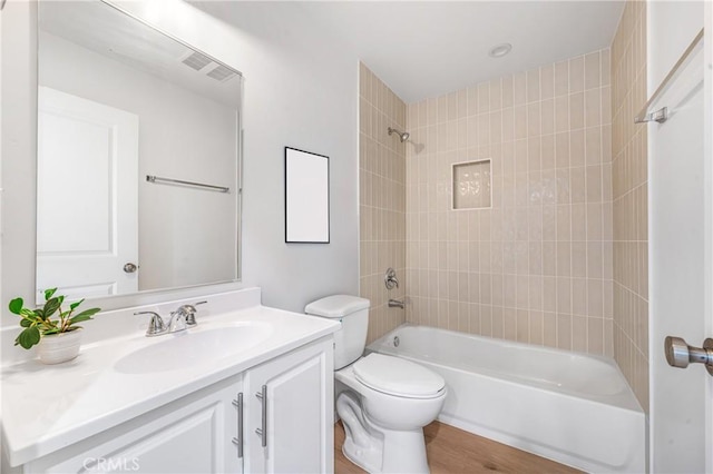 bathroom with toilet, wood finished floors, visible vents, vanity, and shower / bathing tub combination