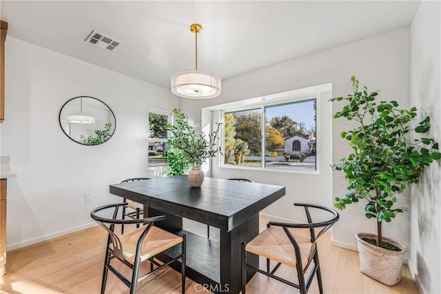 dining area with light wood-type flooring, visible vents, and baseboards