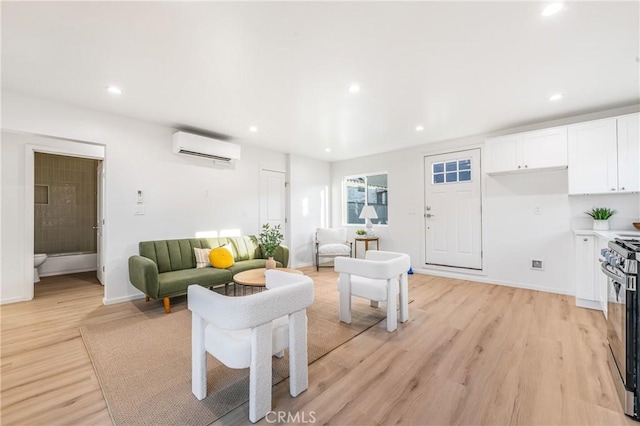 living area featuring a wall unit AC, recessed lighting, light wood-style floors, and baseboards