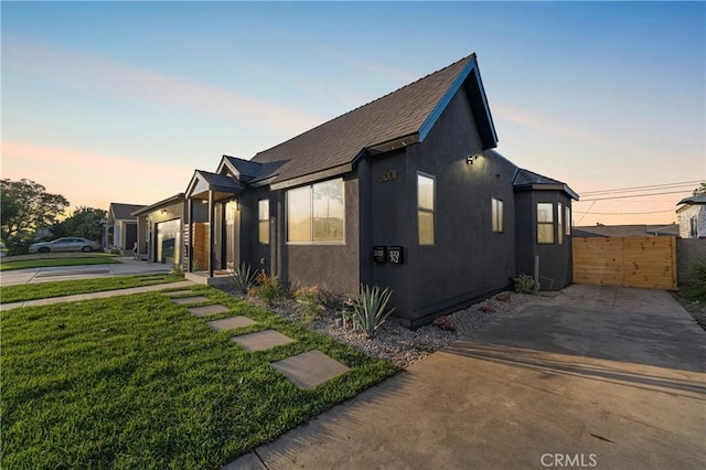 view of home's exterior with a lawn, fence, and stucco siding