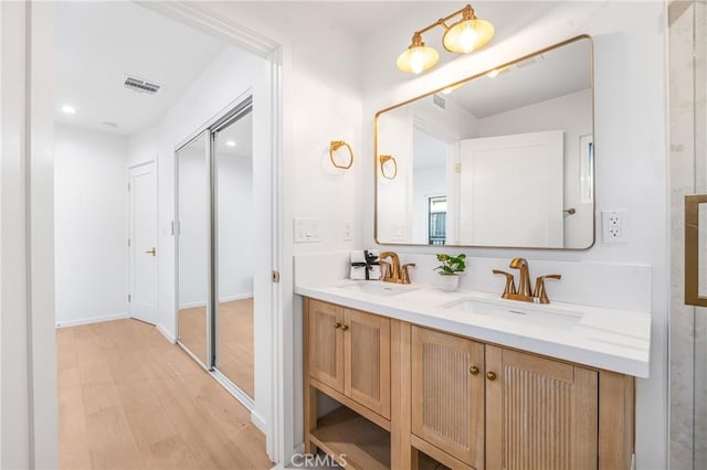 full bath with double vanity, wood finished floors, visible vents, and a sink