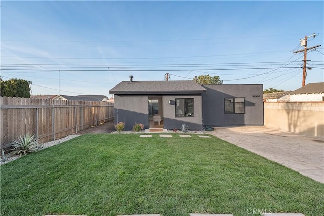 view of front facade with a front lawn, a fenced backyard, and stucco siding