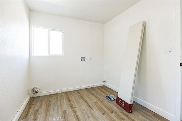 washroom with light wood-type flooring, baseboards, and hookup for a washing machine