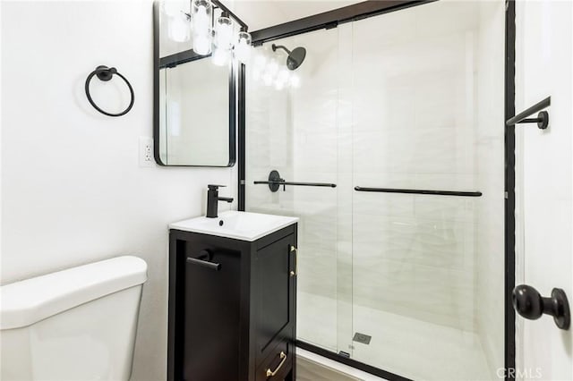 bathroom with a shower stall, toilet, and vanity