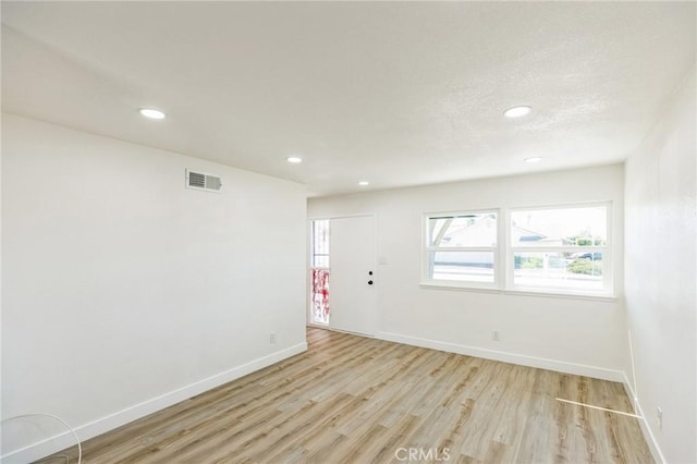 unfurnished room with visible vents, baseboards, recessed lighting, light wood-style floors, and a textured ceiling