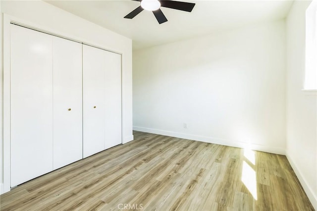 unfurnished bedroom featuring light wood finished floors, ceiling fan, baseboards, and a closet