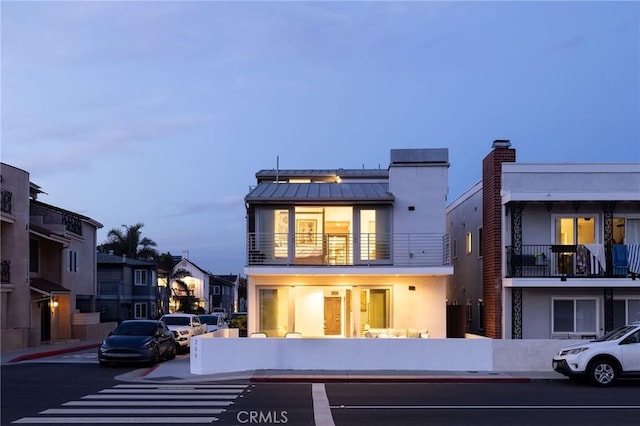 back of property featuring a standing seam roof, metal roof, a balcony, and stucco siding