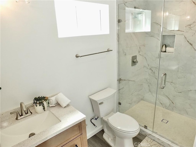 bathroom with toilet, vanity, and a marble finish shower