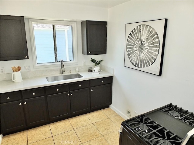 kitchen with dark cabinets, light countertops, a sink, and black gas range oven