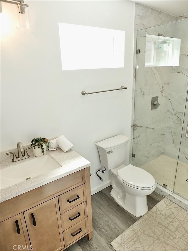 full bath featuring vanity, wood finished floors, a marble finish shower, and toilet