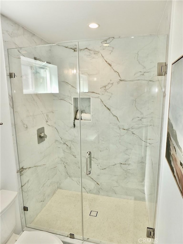 full bath with toilet and a marble finish shower