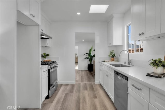 kitchen featuring stainless steel appliances, light countertops, white cabinets, a sink, and under cabinet range hood