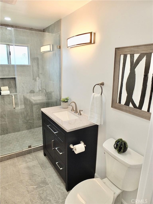 bathroom featuring toilet, a shower stall, and vanity