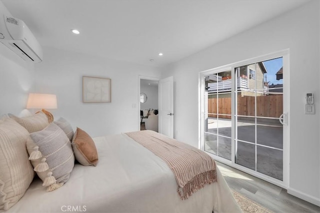 bedroom featuring an AC wall unit, recessed lighting, wood finished floors, and access to exterior