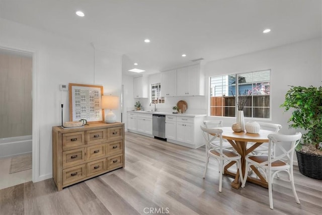 kitchen with light wood finished floors, recessed lighting, light countertops, a sink, and dishwasher