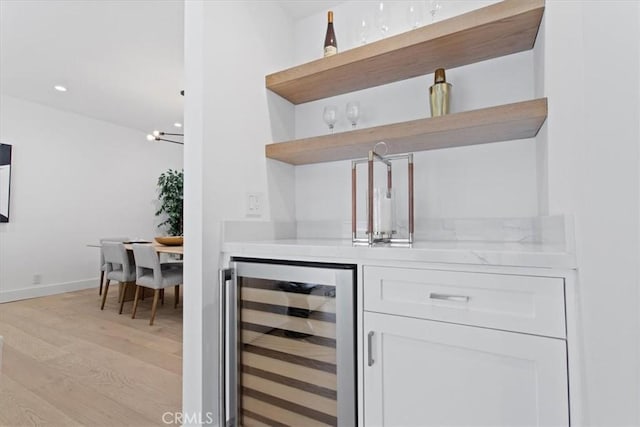 bar with recessed lighting, wine cooler, light wood-style floors, a bar, and baseboards