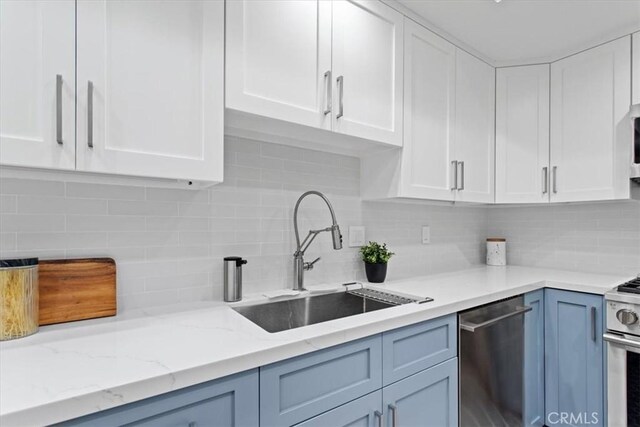 1409 Havenhurst Dr Unit 3, West Hollywood, CA 90046 - kitchen with light stone countertops, decorative backsplash, appliances with stainless steel finishes, white cabinets, and a sink