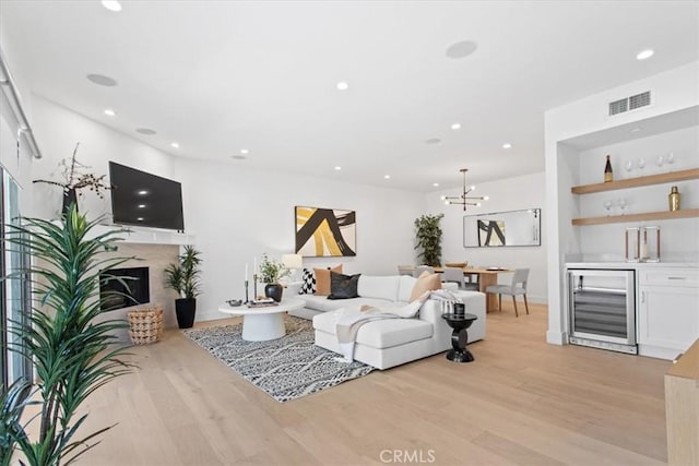 living area featuring light wood finished floors, visible vents, a high end fireplace, beverage cooler, and recessed lighting