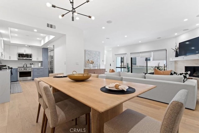 1409 Havenhurst Dr Unit 3, West Hollywood, CA 90046 - dining room with light wood finished floors, visible vents, recessed lighting, a fireplace, and a raised ceiling