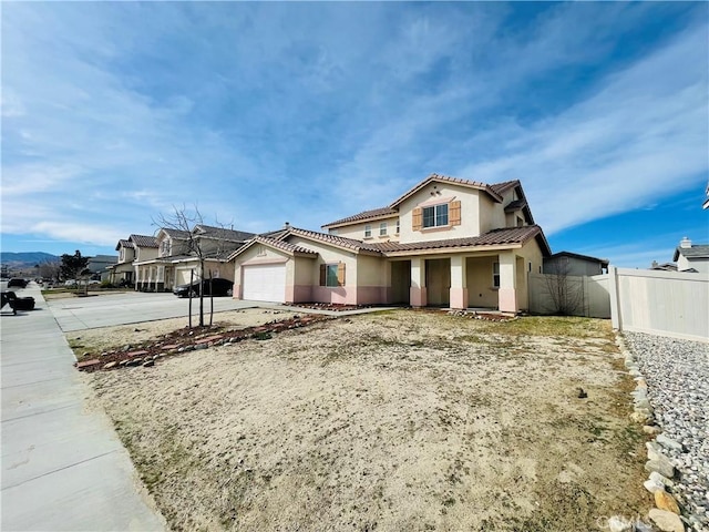 mediterranean / spanish-style home with a tile roof, stucco siding, concrete driveway, an attached garage, and fence