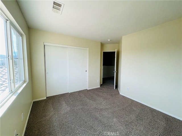 unfurnished bedroom with carpet, a closet, visible vents, and baseboards