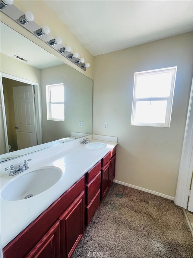 full bathroom with toilet, double vanity, a sink, and visible vents