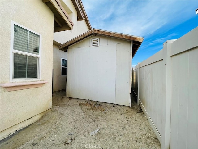 view of side of property with an outbuilding, a fenced backyard, and a storage unit