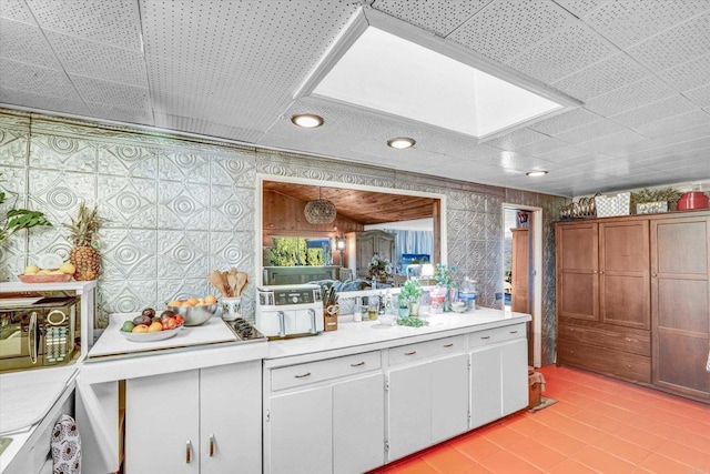 kitchen with light countertops, wallpapered walls, and white cabinetry