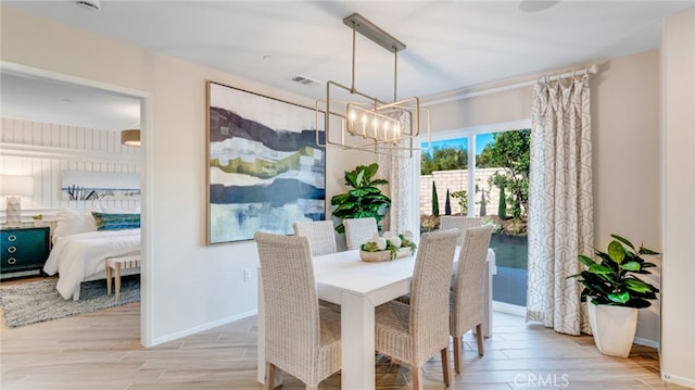 dining area featuring light wood finished floors, baseboards, visible vents, and an inviting chandelier