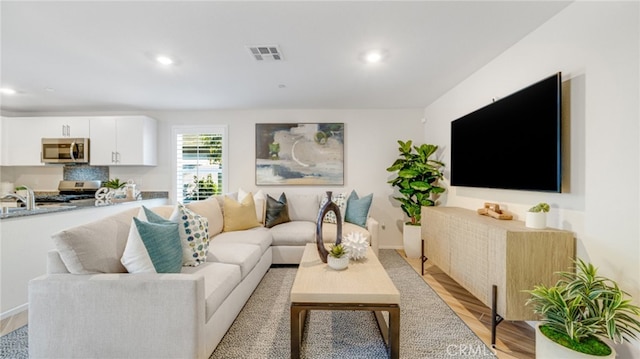 living room featuring recessed lighting, visible vents, and light wood-style floors