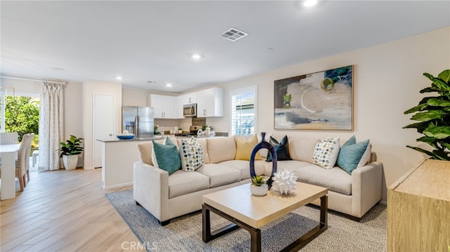 living room featuring recessed lighting, visible vents, plenty of natural light, and light wood-style flooring