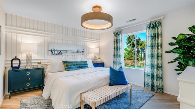 bedroom with light wood finished floors, visible vents, and baseboards