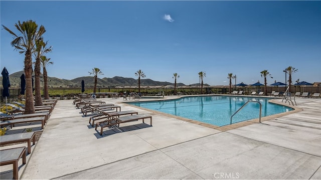 community pool featuring a mountain view, fence, and a patio