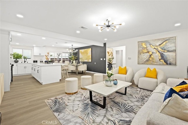 living room with light wood-type flooring, visible vents, a notable chandelier, and recessed lighting